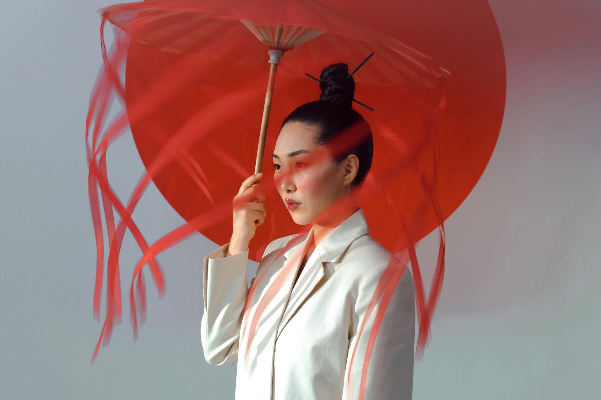 Artistic portrait of a woman holding a red umbrella, highlighting elegance and cultural aesthetics.