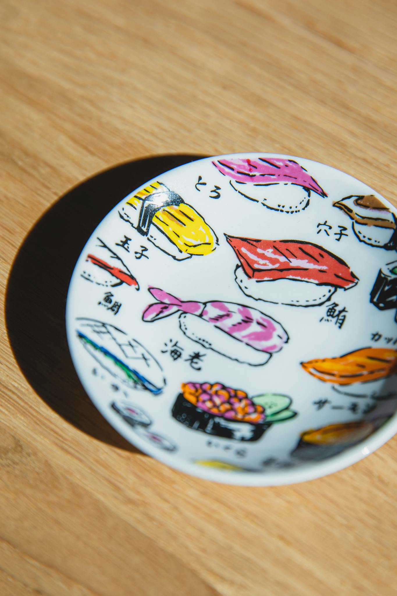 From above of sushi rolls painted on ceramic plate placed on wooden table